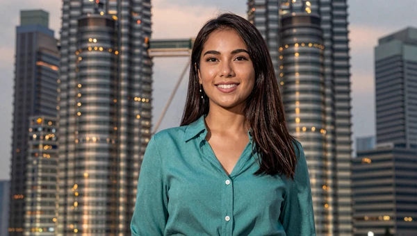 Malaysian woman in modern attire with Kuala Lumpur skyline at dusk