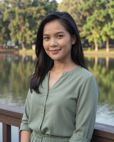 Malee, 28, Thai woman from Khon Kaen in a green blouse at a serene lakeside park
