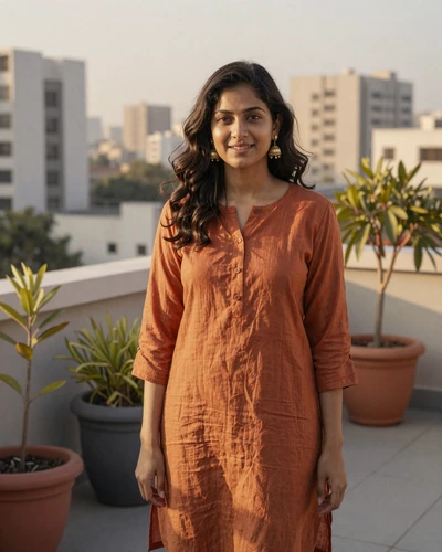 Kavya, 26, Indian woman from Delhi in a burnt orange tunic on a modern rooftop garden