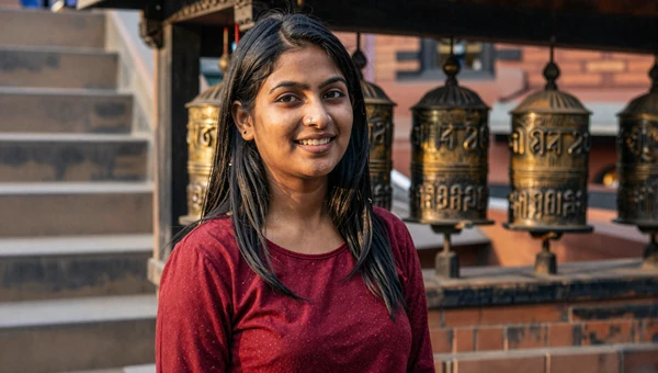 Attractive Nepali woman near Kathmandu temple steps with prayer wheels in golden light