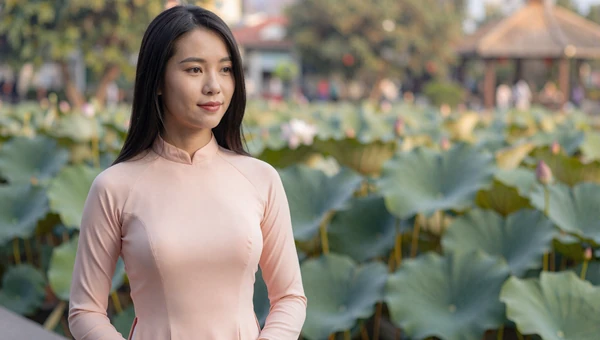 Vietnamese woman in a pastel ao dai near a lotus pond in Hanoi