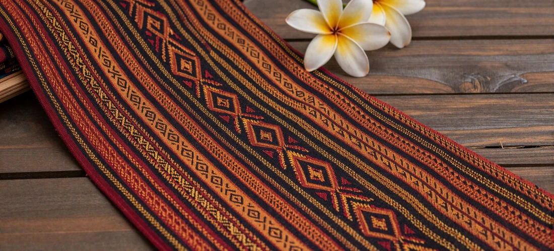 Vibrant handwoven Timorese tais textiles with intricate geometric patterns in red, orange, gold, and black showcasing centuries-old weaving traditions