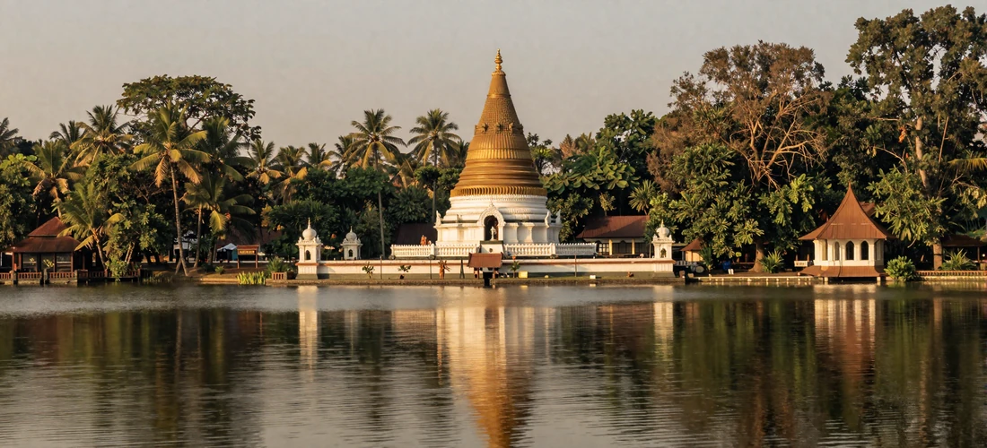 The Temple of the Tooth Relic in Kandy reflected in the peaceful Kandy Lake surrounded by lush tropical trees