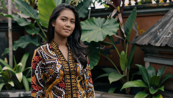 Indonesian woman in colorful batik blouse in a tropical Bali garden